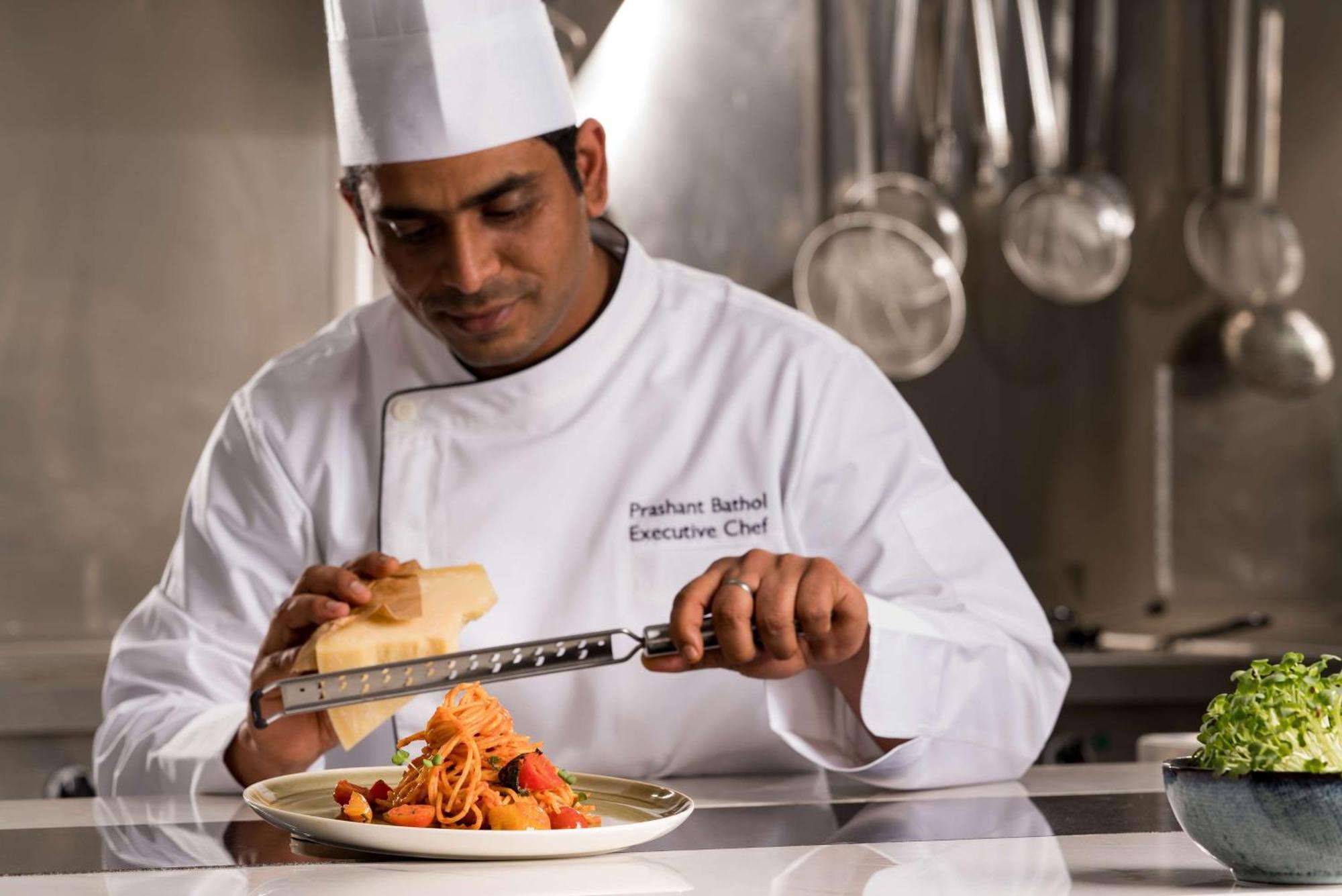 Radisson Blu Hotel Riyadh Qurtuba Extérieur photo A chef grating cheese over a pasta dish